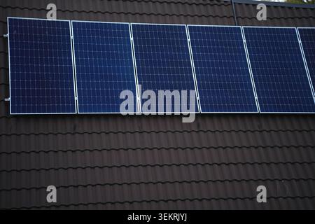 Photovoltaik-Solarpaneele sind auf dem gekachelten Dach eines Wohngebäudes installiert. Horizontales Foto Stockfoto