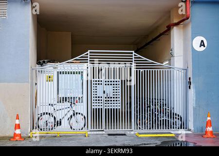 Batumi, Georgia - 30. Mai 2026: Verschlossenes elektronisches Stahltor am Eingang des Wohngebäudes, das zur Aufzugshalle mit gesichertem Fahrradparkplatz führt. Stockfoto