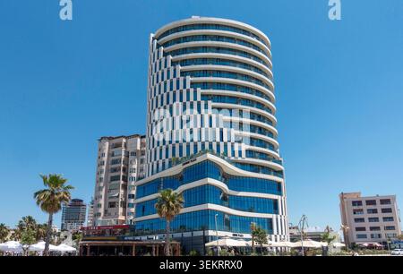 Das moderne Hotel Crowne Plaza steht unter einem klaren blauen Himmel in Durres, Albanien, flankiert von Palmen. Stockfoto
