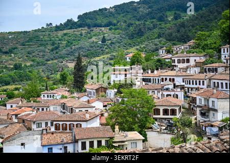 Panoramablick auf traditionelle Häuser im osmanischen Stil mit Terracotta-Dächern auf einem grünen Hügel in einem türkischen Dorf; Reise- und Architekturszene Stockfoto