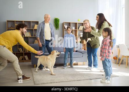 Fröhliche Eltern Kinder und Großeltern spielen mit Labrador Hund in gemütlichem Haus Stockfoto
