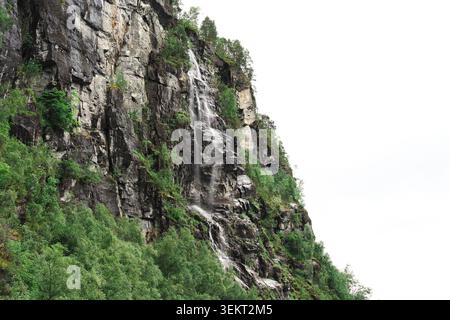 Hoher Wasserfall, der über felsige Fjordklippen in der Nähe von Bergen, Norwegen, stürzt. Stockfoto