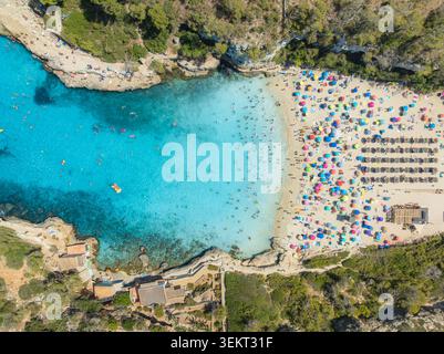 Blick aus der Vogelperspektive auf bunte Sonnenschirme, überfüllten Sandstrand, blaues Meer Stockfoto