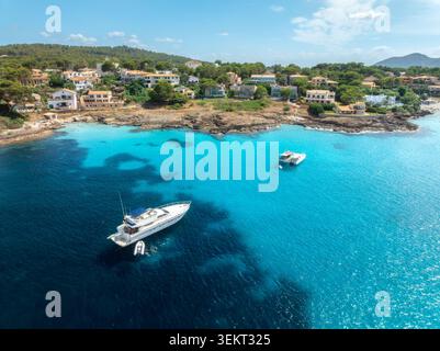 Blick aus der Vogelperspektive auf Yachten und Boote, die in der türkisfarbenen Meeresbucht vor Anker liegen Stockfoto