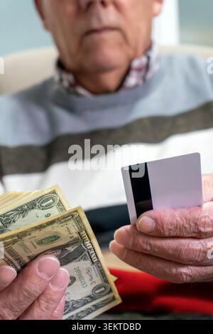 Senior-Mann, der Bargeld mit leerer Kreditkarte vergleicht Stockfoto