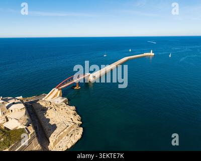 Aus der Vogelperspektive auf den Leuchtturm von Saint Elmo und die rote Bruchbrücke, die sich in das tiefblaue Mittelmeer in Valletta, Port Region, Malta erstreckt. Stockfoto