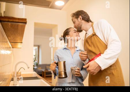 Zwei junge Leute trinken Kaffee in der Küche und fühlen sich fröhlich und verliebt Stockfoto
