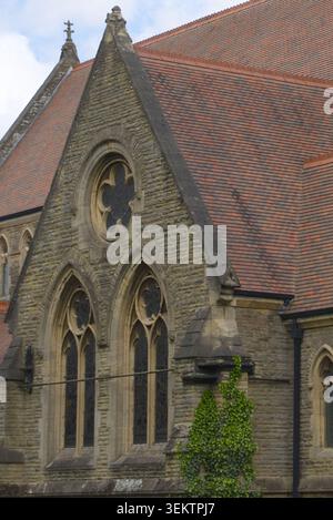 Aufnahmen aus einem niedrigen Winkel von einer historischen gotischen Steinkirche mit Bogenfenstern, Tracery-Mauerwerk und einem Schieferdach Stockfoto