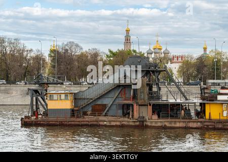 Rostiges Dredger-Barge, Das Auf Dem Fluss Arbeitet, Schwere Krane Und Förderanlagen An Deck, Industriekübel Mit Fahrerkabine, Krautige Küstenszene Stockfoto