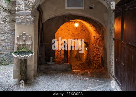 Ein schmaler Steinweg windet sich durch das mittelalterliche Hügeldorf Dolceacqua, Italien, in den Hügeln über Ventimiglia in der Region Ligurien. Stockfoto