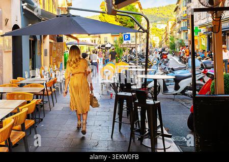 Fußgänger schlendern durch das lebhafte Viertel Vieille Ville (Altstadt) von Nizza, Frankreich, bekannt für seine engen, geschäftigen Straßen, die mit Straßencafés gesäumt sind. Stockfoto