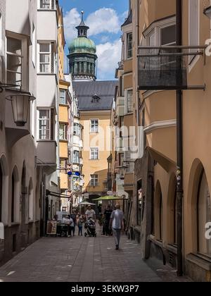 Ebenerdiger Blick auf eine enge historische Gasse in der Innsbrucker Altstadt, eingerahmt von hohen pastellfarbenen Tiroler Stadthäusern mit Arkadenboden Stockfoto