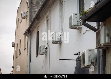 Mehrere Klimaanlagen, die an einer Außenfassade des Gebäudes montiert sind und Kondensatoren, Halterungen, Rohre und Lüftungsgeräte entlang einer zeigen Stockfoto