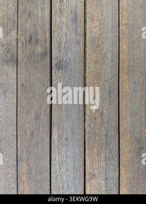 Eine hochwinklige Aufnahme aus verwitterten braunen Holzdielen, die vertikal angeordnet sind und natürliche Kornmuster, rustikale Mängel und dunkle Lücken zeigen Stockfoto