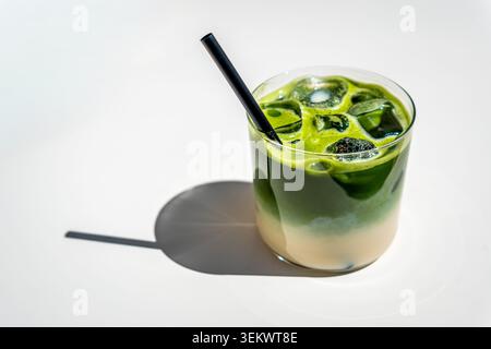 Ein gefrorener Matcha-Latte mit Hafermilch auf einem weißen Tisch im Glas Stockfoto