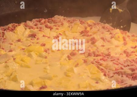 Zubereitung von Tartiflette, ein traditionelles französisches Gericht mit Jakobskartoffeln, Speck und Käse, in großem Kessel Stockfoto