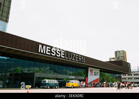 Luzern, Schweiz, 30. Mai 2026. Wide Shot zeigt das moderne Glas- und Stahlgebäude der Messe Luzern mit Besuchern und dem klassischen Volkswagen campe Stockfoto