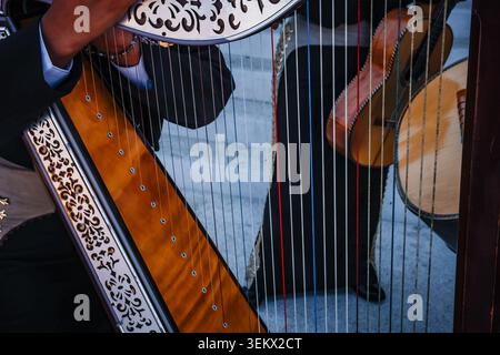 Nahaufnahme eines Musikers, der eine traditionelle mexikanische Mariachi-Harfe spielt. Volksmusik mit Streichinstrumenten und Musikern in charro-Anzug Stockfoto