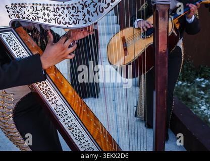 Nahaufnahme eines Musikers, der eine traditionelle mexikanische Mariachi-Harfe spielt. Volksmusik mit Streichinstrumenten und Musikern in charro-Anzug Stockfoto