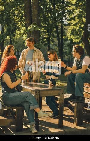 Eine Gruppe junger Freunde isst Eis am Parktisch mit Retro-Effekt. Stockfoto