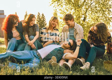 Gruppe von Freunden, die sich auf dem Gras entspannen und im Retro-Sommer lachen. Stockfoto