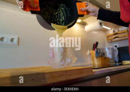 Hände, die Choux-Teig in einer Küche zubereiten Stockfoto