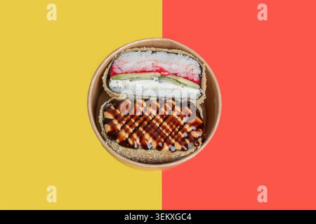 Ein köstlicher Sushi-Burger mit verschiedenen Füllungen auf farbigem und weißem Hintergrund, garniert mit Sesamsamen und grünen Zwiebeln. Isoliert auf einem Hinterwäldler Stockfoto