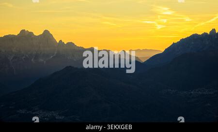 La Valle Agordina, Italien - 15.10.2021: Dramatische Alpenlandschaft mit mehrschichtigen Bergkämmen unter einem hellen goldenen Abendglühen Stockfoto