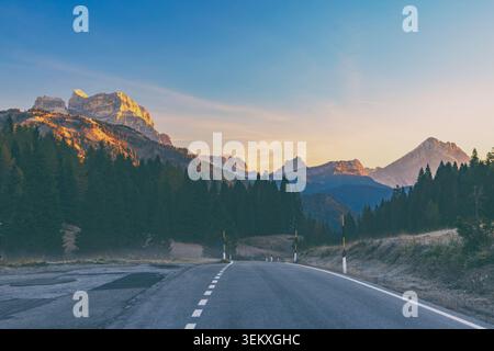 Chiesa, Italien - 17.10.2021: Majestätische Kalksteinberge, die im Morgenlicht über einer ruhigen Autobahn und nebeligen Kiefernwäldern leuchten Stockfoto