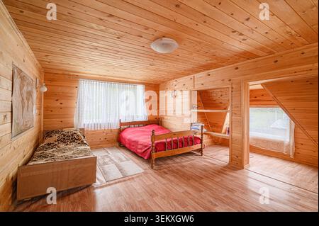 Gemütliche Holzkabine mit zwei Betten, Fenstern mit Spitzenvorhängen und Regalen. Stockfoto