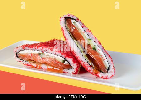 Ein Sushi-Sandwich mit verschiedenen Füllungen auf farbigem und weißem Hintergrund, garniert mit Sesamsamen und grünen Zwiebeln. Isoliert auf einem Hintergrund. Modus Stockfoto
