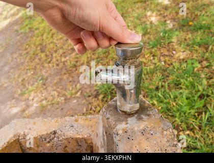 Öffentlicher Trinkbrunnen und Hand, die an heißem Tag Relief suchen Stockfoto