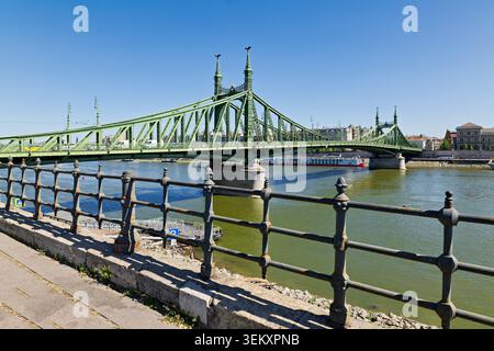 Szabadsag HID verbindet Buda und Pest über die Donau mit klarem Himmel. Die Leute laufen den Weg am Wasser entlang. Stockfoto