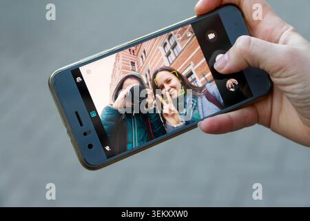 Person, die ein Selfie mit einem Smartphone macht, das zwei junge Frauen zeigt Stockfoto