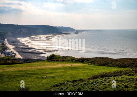 Atemberaubender Panoramablick auf die Küste von Dieppe. Ein üppiges grünes Feld hebt sich im Vordergrund hervor, während der Hintergrund das Meer zeigt Stockfoto