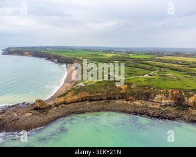 Weite Luftaufnahme des Vorgebietes Pointe du hoc. Das Bild zeigt steile Klippen, felsige Küsten in türkisfarbenem Wasser und ein Netz von Wegen, die sich durchwinden Stockfoto
