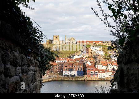 Whitby, Yorkshire, Großbritannien, England, Ein gerahmter Blick von einer alten Steinmauer über den oberen Hafen in Richtung East Cliff in Whitby. Die Stockfoto
