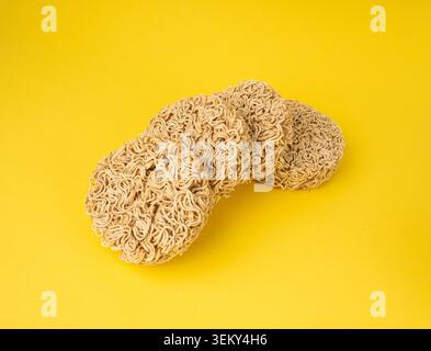 Rohe Nudeln, trockene runde Ramen Nudeln Set, ungekochte Korea Vermicelli, schnelle chinesische Roggen Weizen Pasta, Instant Makkaroni auf gelbem Hintergrund Stockfoto
