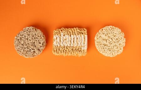 Verschiedene Rohnudeln, trockene runde Ramen-Nudeln, verschiedene ungekochte Korea Vermicelli, schnelle chinesische Weizennudeln, Instant Macaroni Mix auf Orange Bac Stockfoto