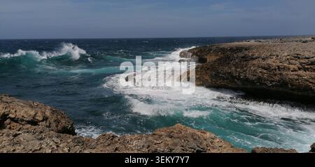 Raue Kalksteinfelsen an der Nordküste Curacaos, wo mächtige karibische Wellen gegen felsige Klippen und natürliche Meeresformationen krachen. Stockfoto