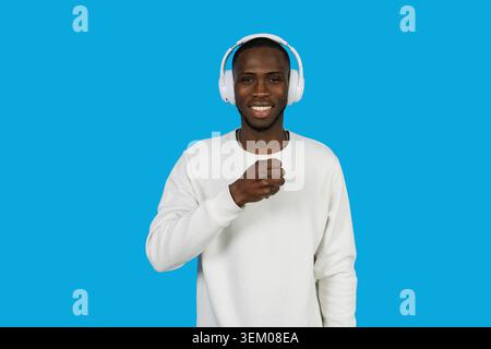 Junger Mann lächelt und hört Musik über weiße Kopfhörer Stockfoto