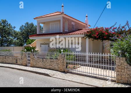 Monte Canelas Algarve Portugal, Ein wunderschönes zweistöckiges Haus mit einem roten Ziegeldach, weißen Fensterläden und blühenden Weinstöcken Stockfoto