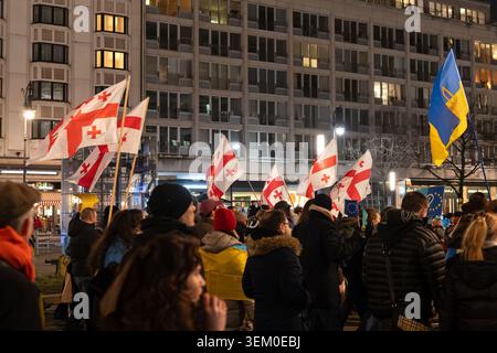 Berlin, Deutschland - 24. Februar 2026: Eine Menge marschiert nachts mit mehreren georgischen Nationalflaggen, die während eines pro-ukrainischen EM über den Teilnehmern gehisst werden Stockfoto