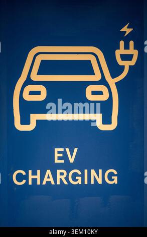 Gelbes Symbol für das Aufladen von Elektrofahrzeugen und Text auf blauem Hintergrund Stockfoto