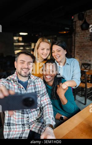 Verschiedene Gruppe lächelnder Freunde, die Selfie im Restaurant machen Stockfoto