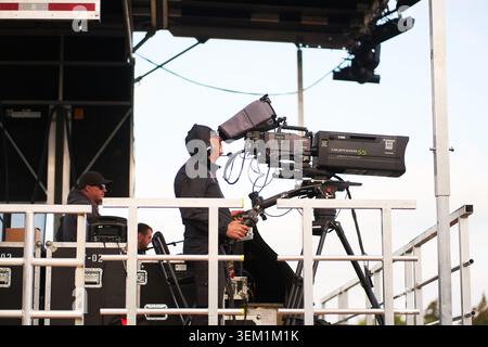 Professioneller Fernsehkameramann, der eine große Videokamera auf einem Stativ auf einer Veranstaltungsbühne im Freien bedient. 07.07.2023 - Calgary, Kanada Stockfoto