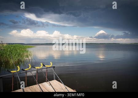 Angelruten Am Holzpier Über Dem Calm Lake Vor Dem Sommersturm Stockfoto