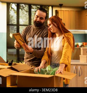 Junge Paare, die ihre Dekorationen in ihrem neuen Haus auspacken, in melancholischer Wut, ihre Erinnerungen zusammen zu pflegen. Hausbesitzer, die Spaß an der Umsiedlung haben, ihre Wohnung umgestalten. Stockfoto