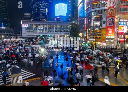 Weitwinkelblick bei Nacht auf Shibuya Scramble Crossing mit leuchtenden Neonlichtern, die sich in nassen Straßen spiegeln, Tokio Stockfoto