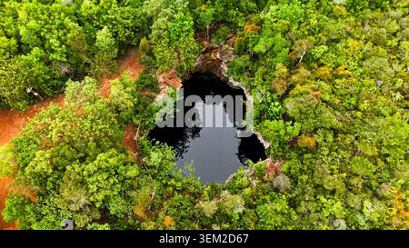 Blick aus der Vogelperspektive auf das Sapphire Blue Hole, umgeben von dichtem grünen tropischen Wald und einer kleinen hölzernen Plattform in der Bluff Settlement, North Eleuthera, The Stockfoto